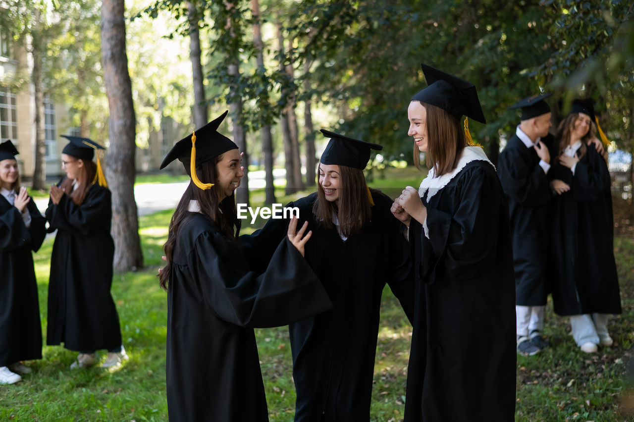 rear view of man wearing graduation gown standing in forest