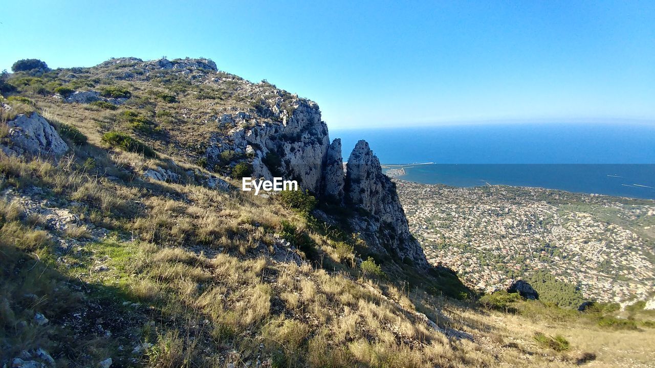 SCENIC VIEW OF ROCKY MOUNTAINS AND SEA AGAINST CLEAR BLUE SKY