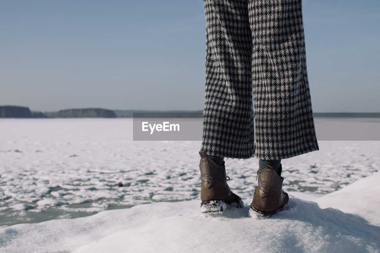 Young girl standing near frozen lake.