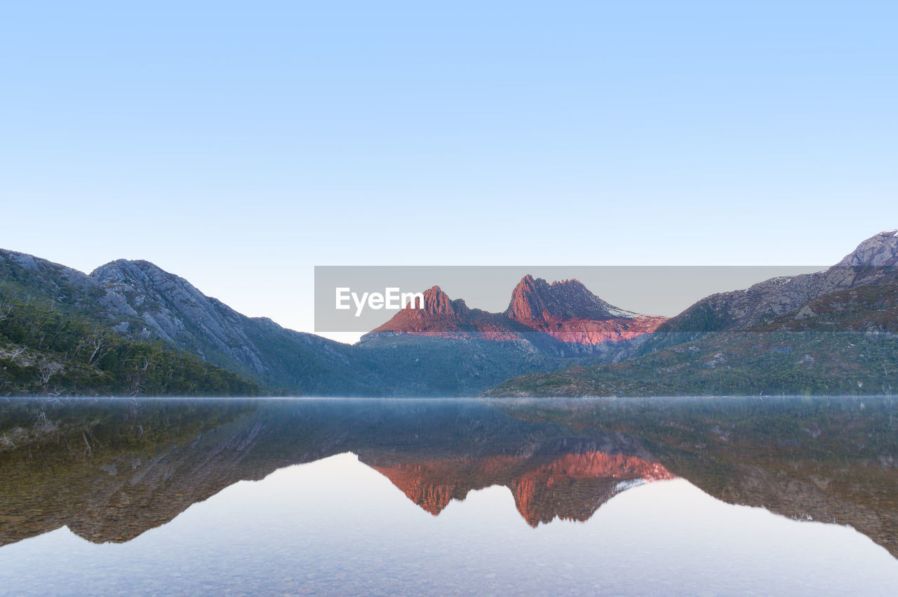 Cradle mountain on sunrise reflected on mirror like lake dove water with subtle mist