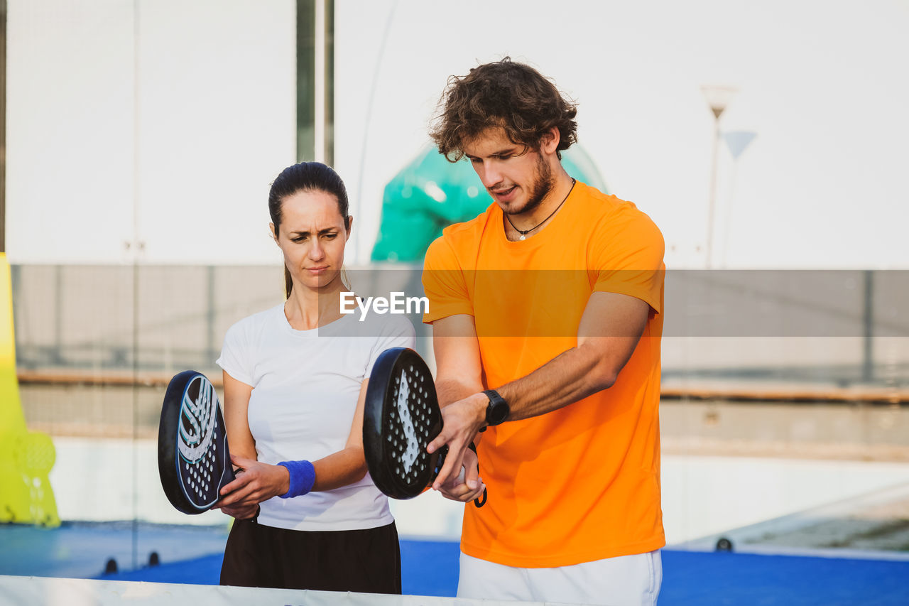 Man and woman holding tennis racket