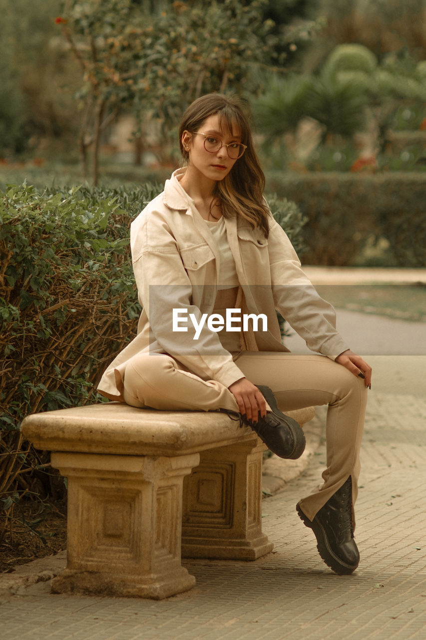 Portrait of young woman sitting on bench at park