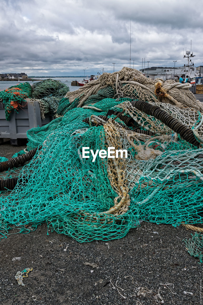 Fishing nets at harbor against cloudy sky