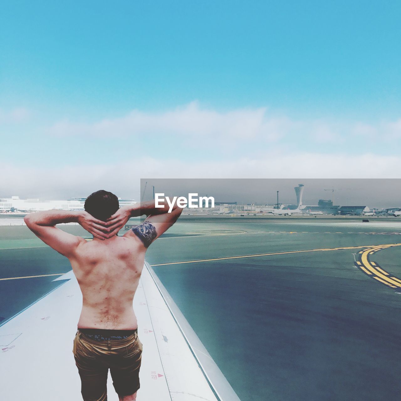 Rear view of shirtless man standing in city against sky