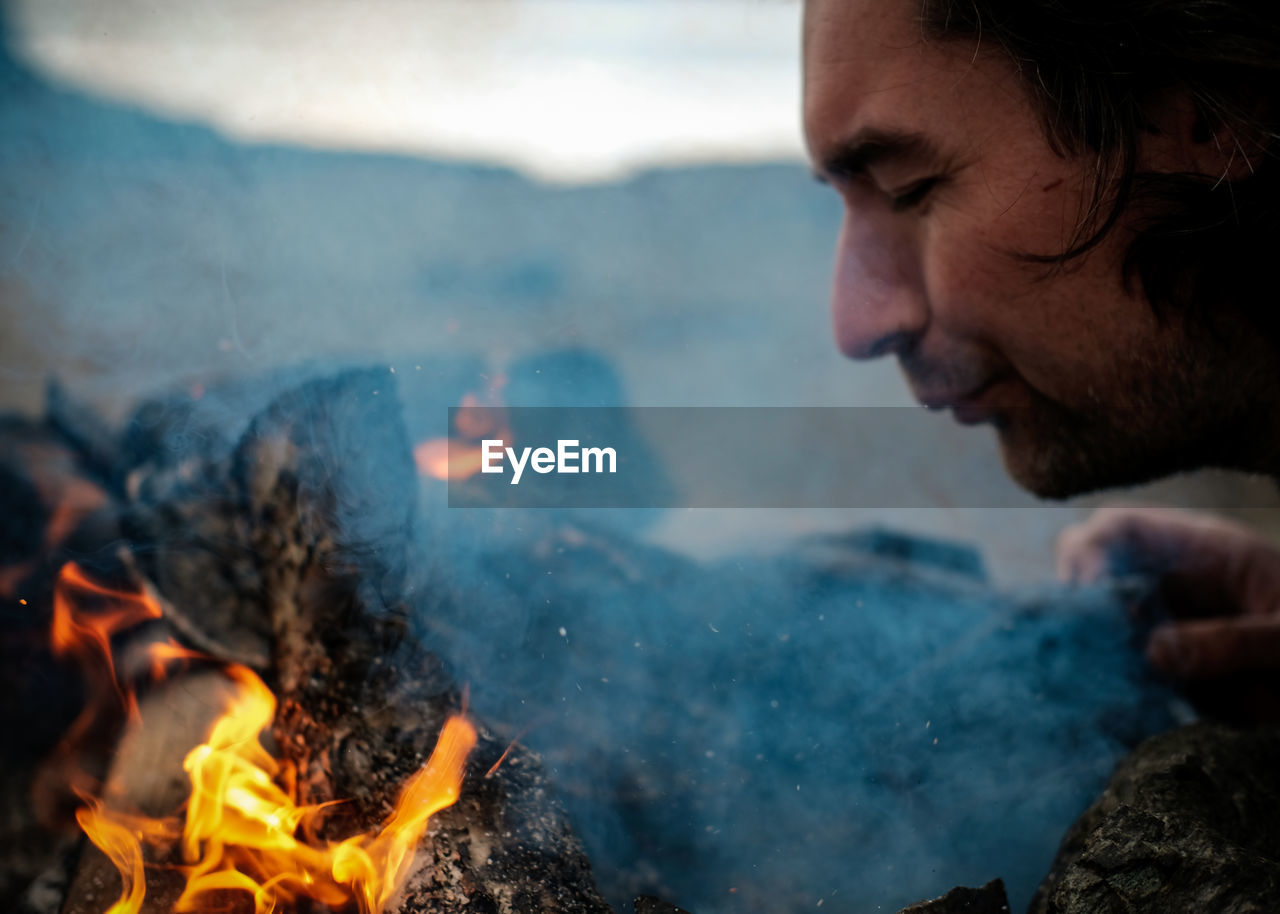 Close-up of man burning campfire outdoors