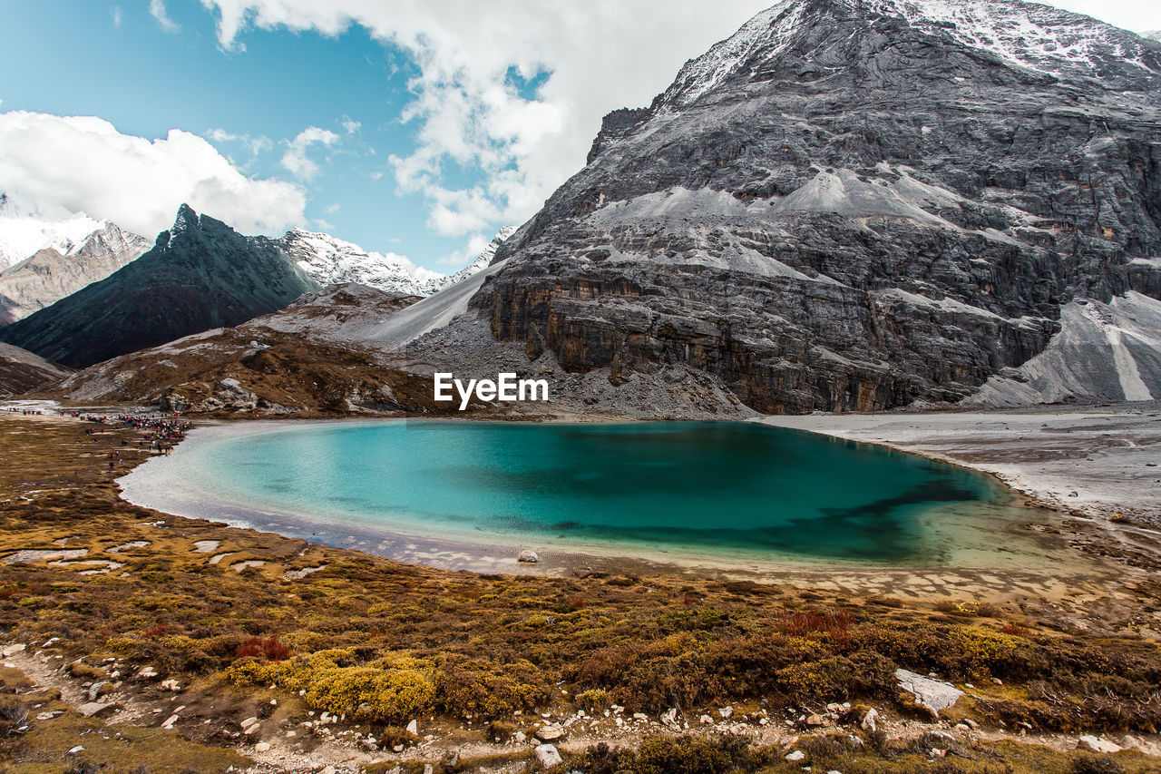 Scenic view of lake by snowcapped mountains against sky