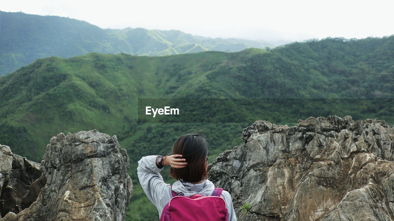 Rear view of woman looking away while standing against landscape