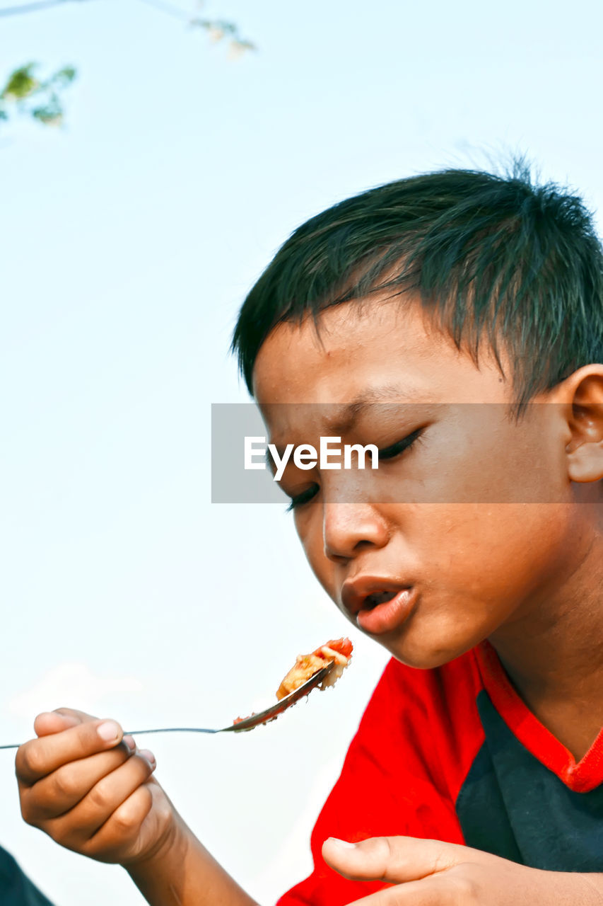 Close-up of boy blowing hot food on spoon