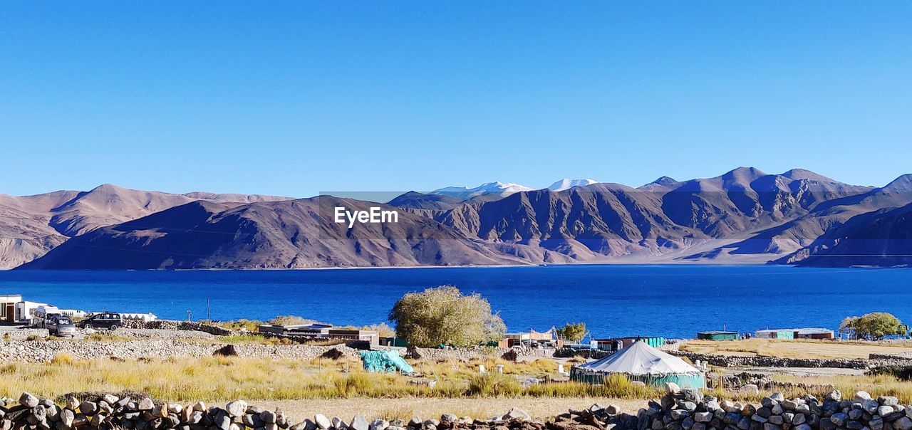 Scenic view of lake and mountains against clear blue sky