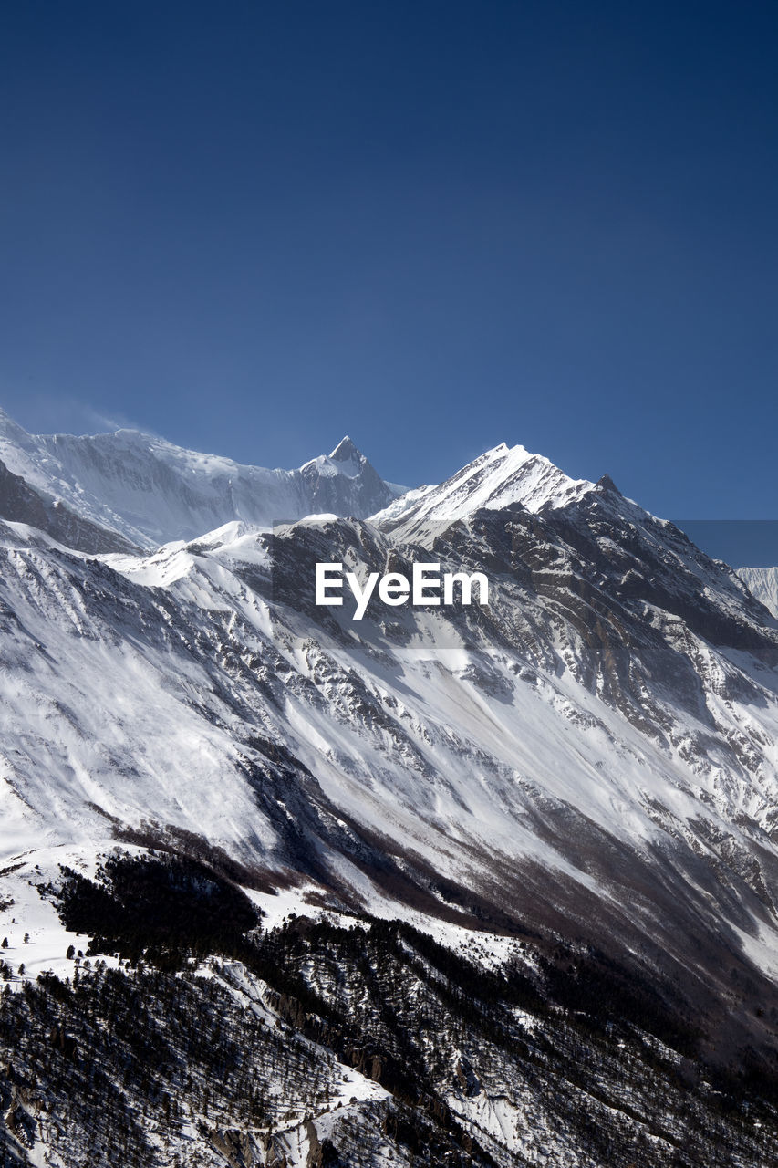 Scenic view of snowcapped mountains against clear blue sky