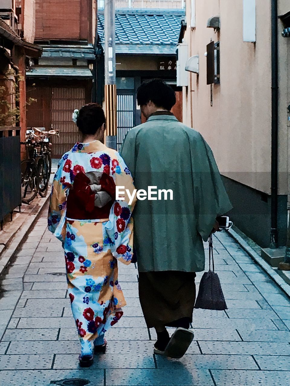 REAR VIEW OF A COUPLE WALKING ON THE ROAD