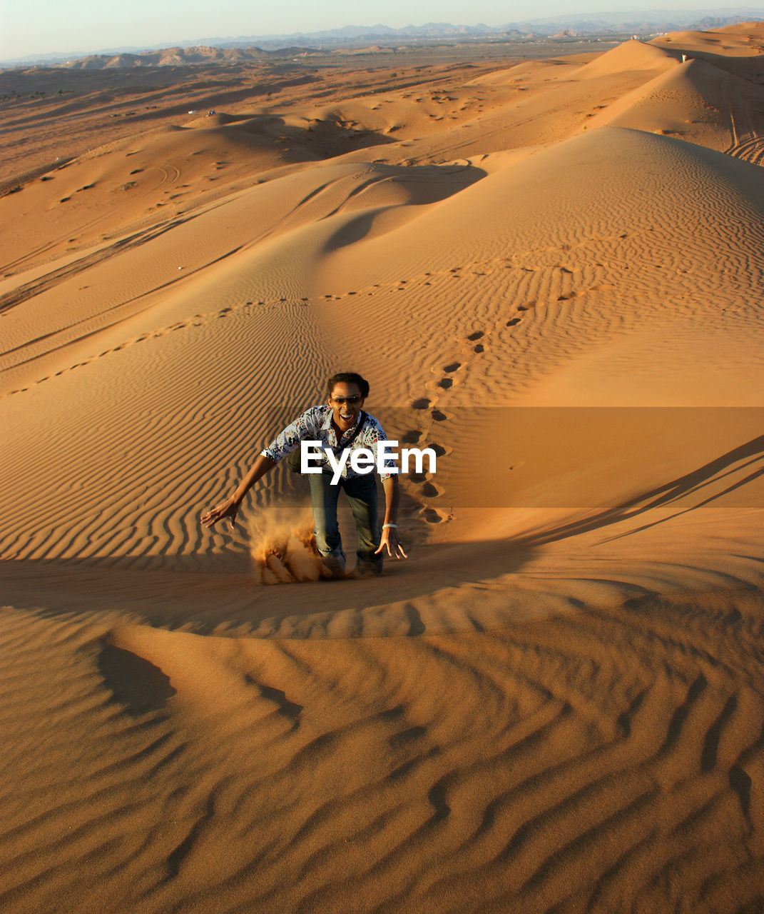 Portrait of happy man walking on sand dune