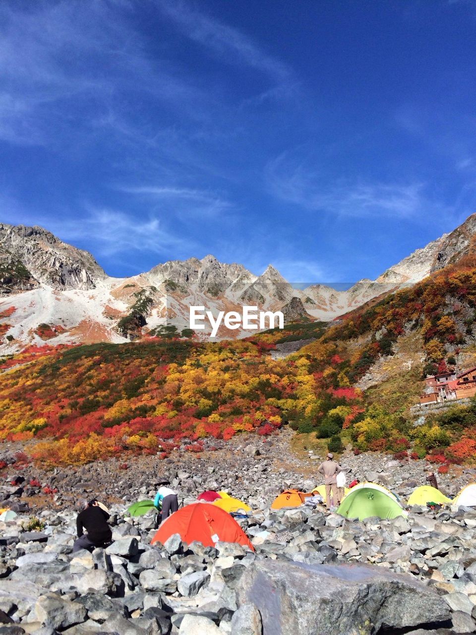 People at tents against autumnal landscape