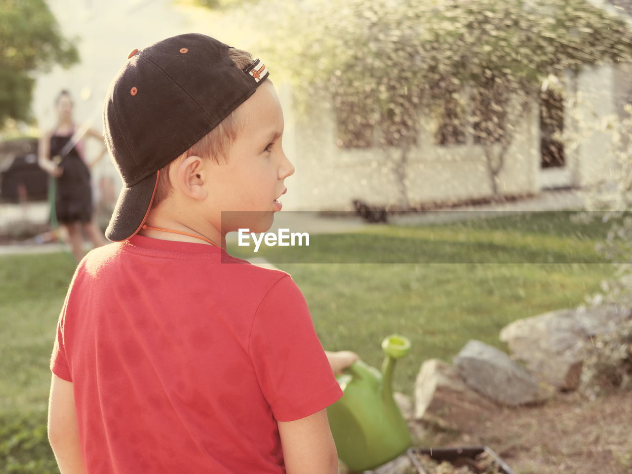 SIDE VIEW OF BOY LOOKING THROUGH CAMERA OUTDOORS