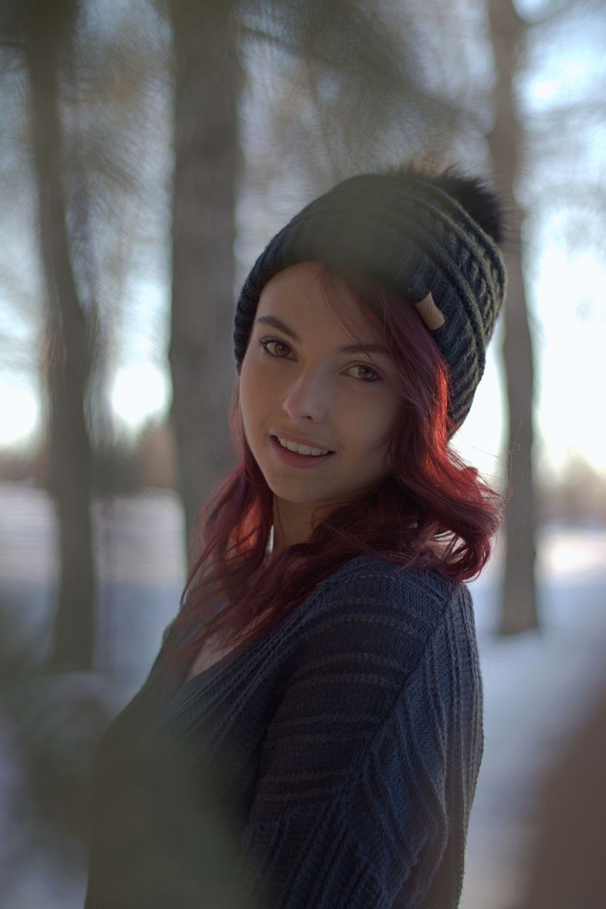 Portrait of smiling young woman in forest during winter