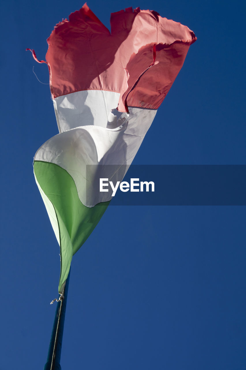 Low angle view of flag against clear blue sky