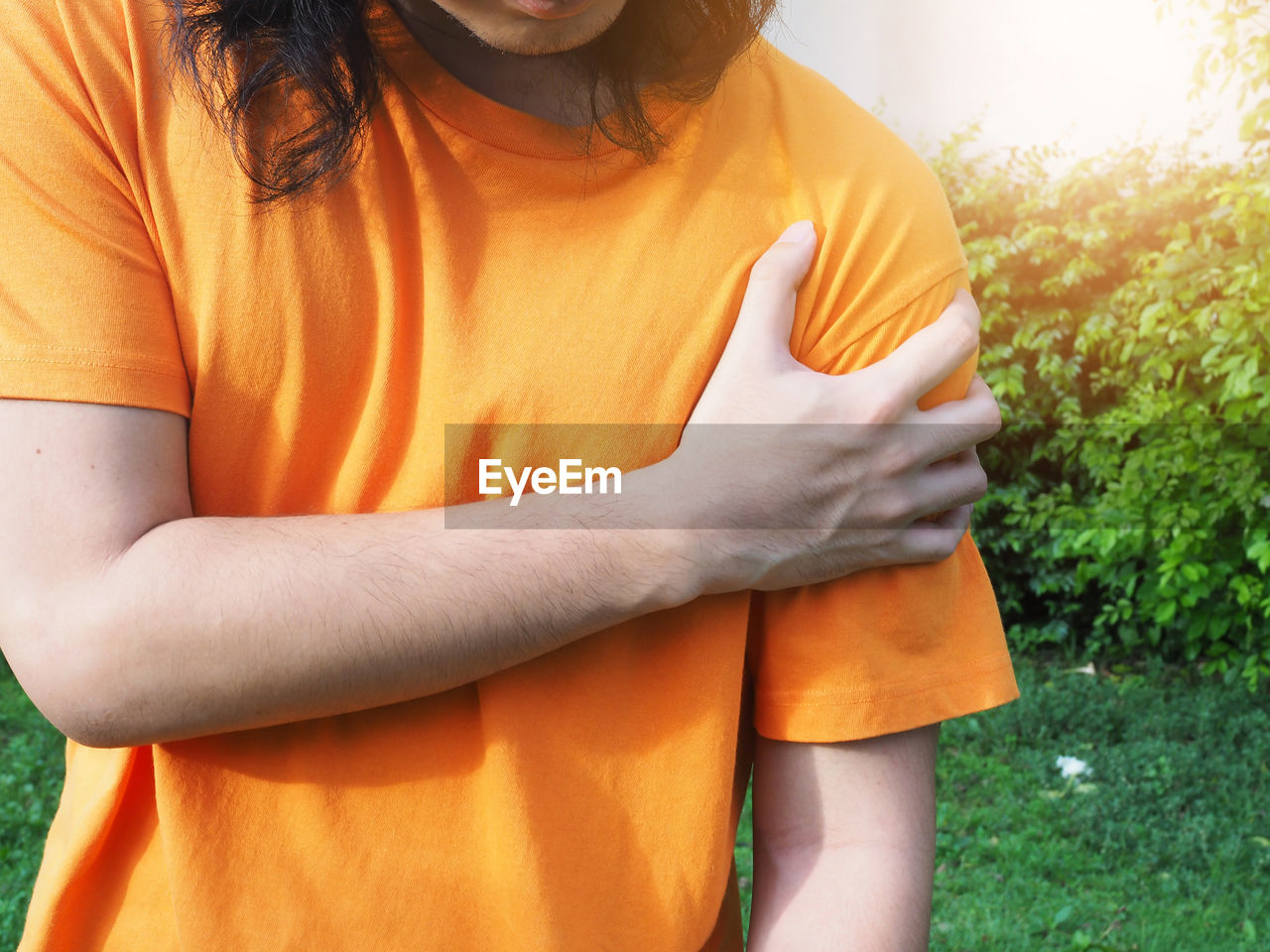 MIDSECTION OF WOMAN WITH ORANGE HAIR STANDING AGAINST PLANTS