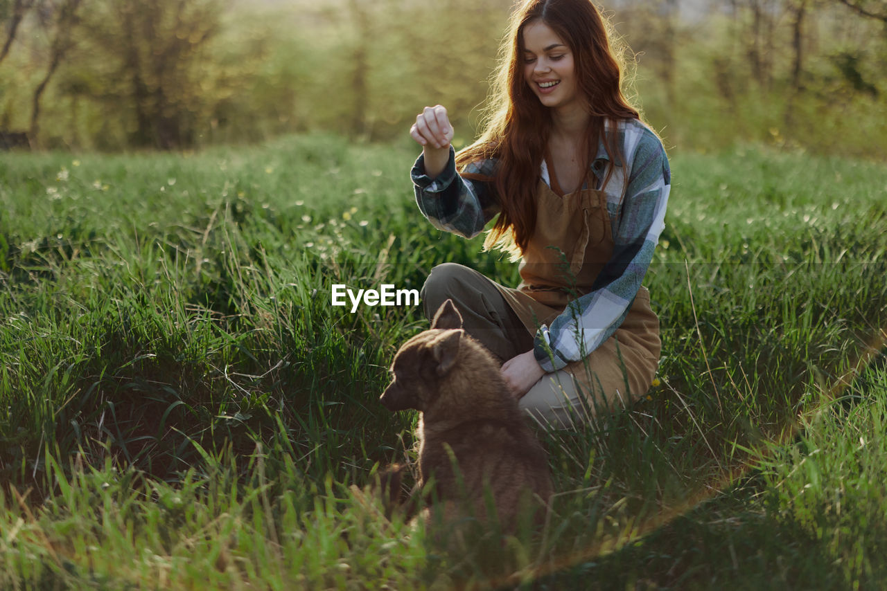 portrait of smiling young woman sitting on grassy field