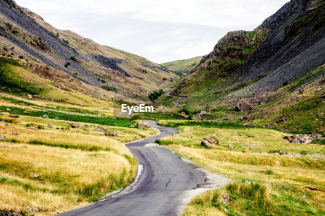 Road leading towards mountains against sky