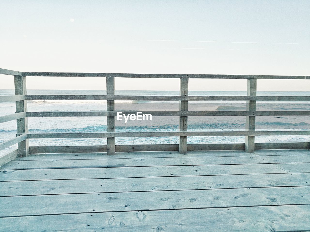 CLOSE-UP OF RAILING AGAINST SEA AND CLEAR SKY