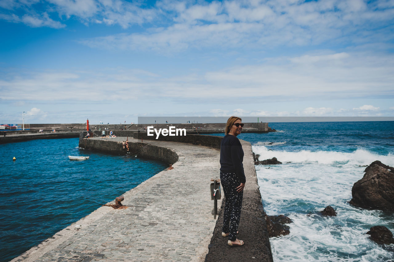 Full length of woman walking on retaining wall at pier