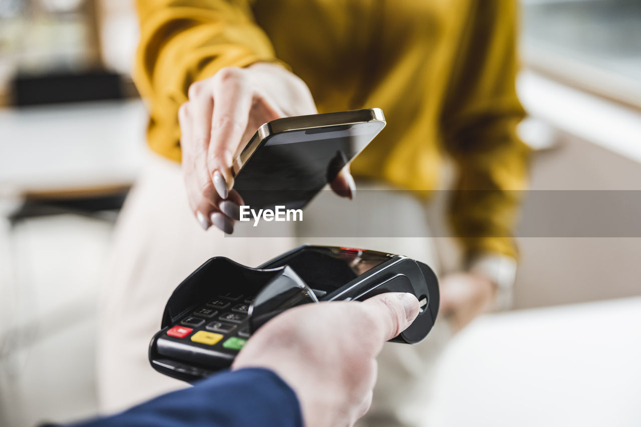 Hand of young businesswoman paying through smart phone