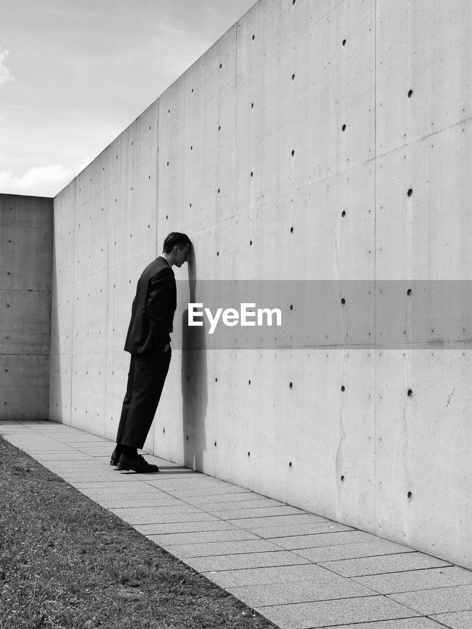 Full length of depressed man standing by wall