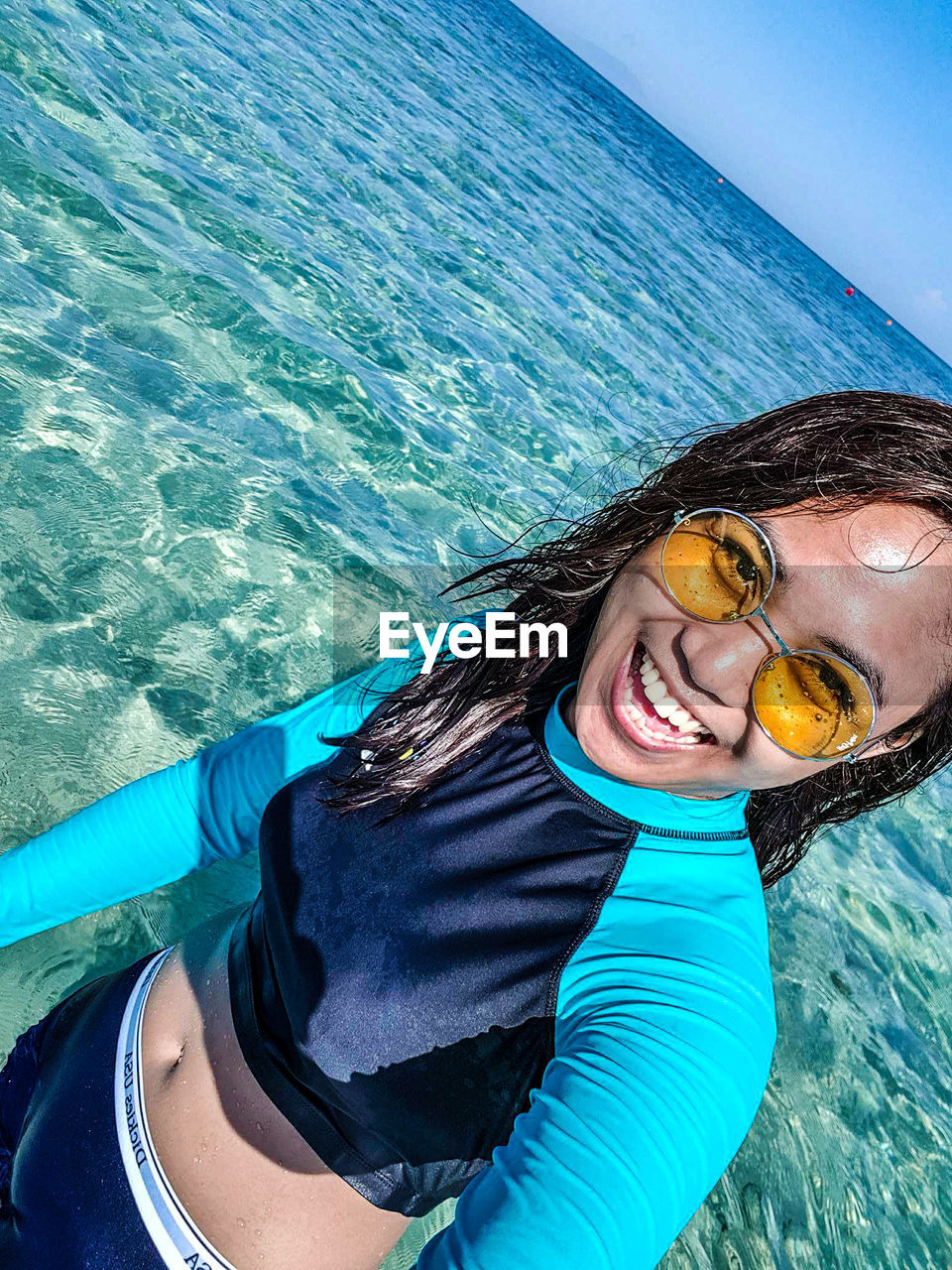 Portrait of happy young woman wearing sunglasses in sea