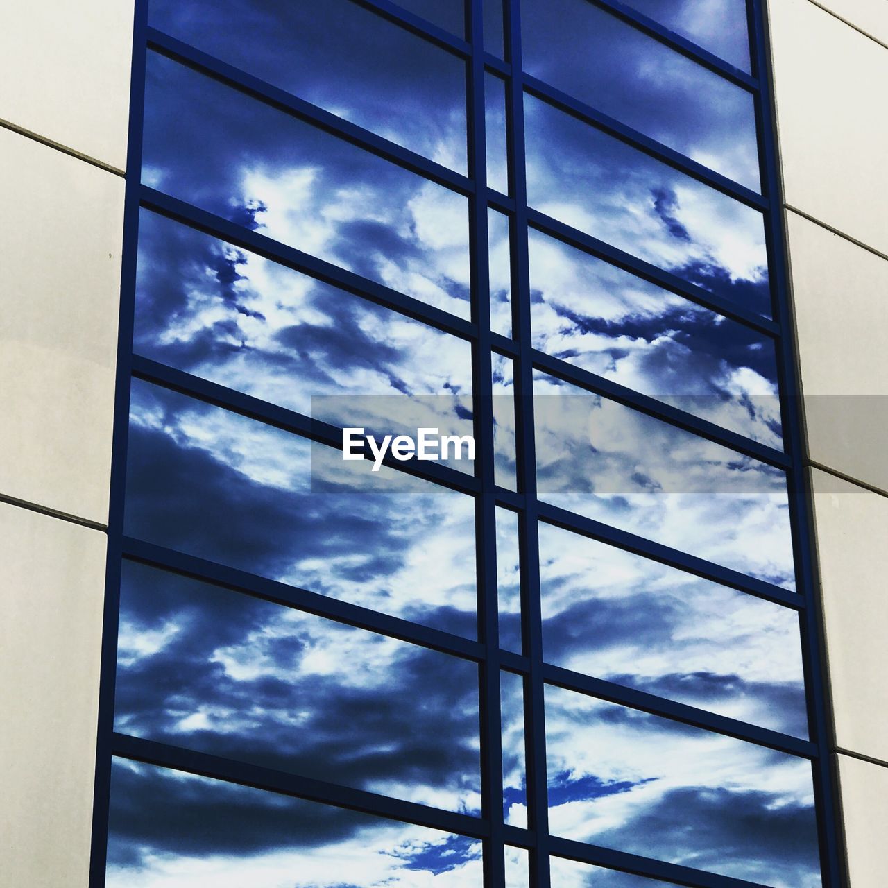LOW ANGLE VIEW OF SKY AND CLOUDS REFLECTING IN WINDOW