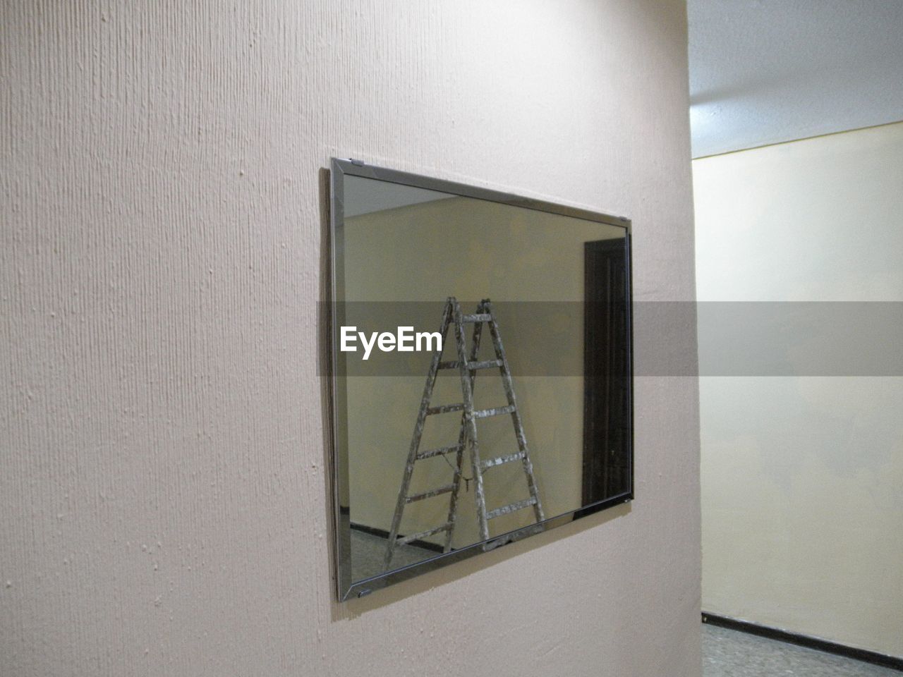 Wooden ladder reflecting on mirror in room