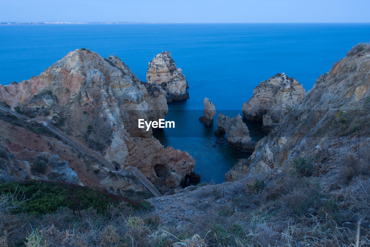 Scenic view of rocks in sea against blue sky