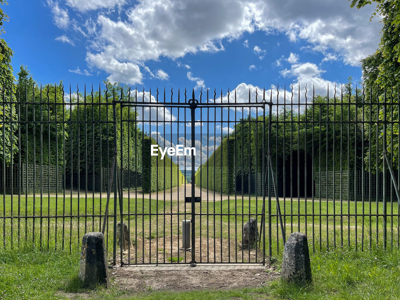 cloud, sky, plant, fence, nature, security, protection, outdoor structure, tree, architecture, gate, home fencing, landscape, no people, grass, environment, day, outdoors, green, land, built structure, metal, garden, blue, estate, field, travel destinations