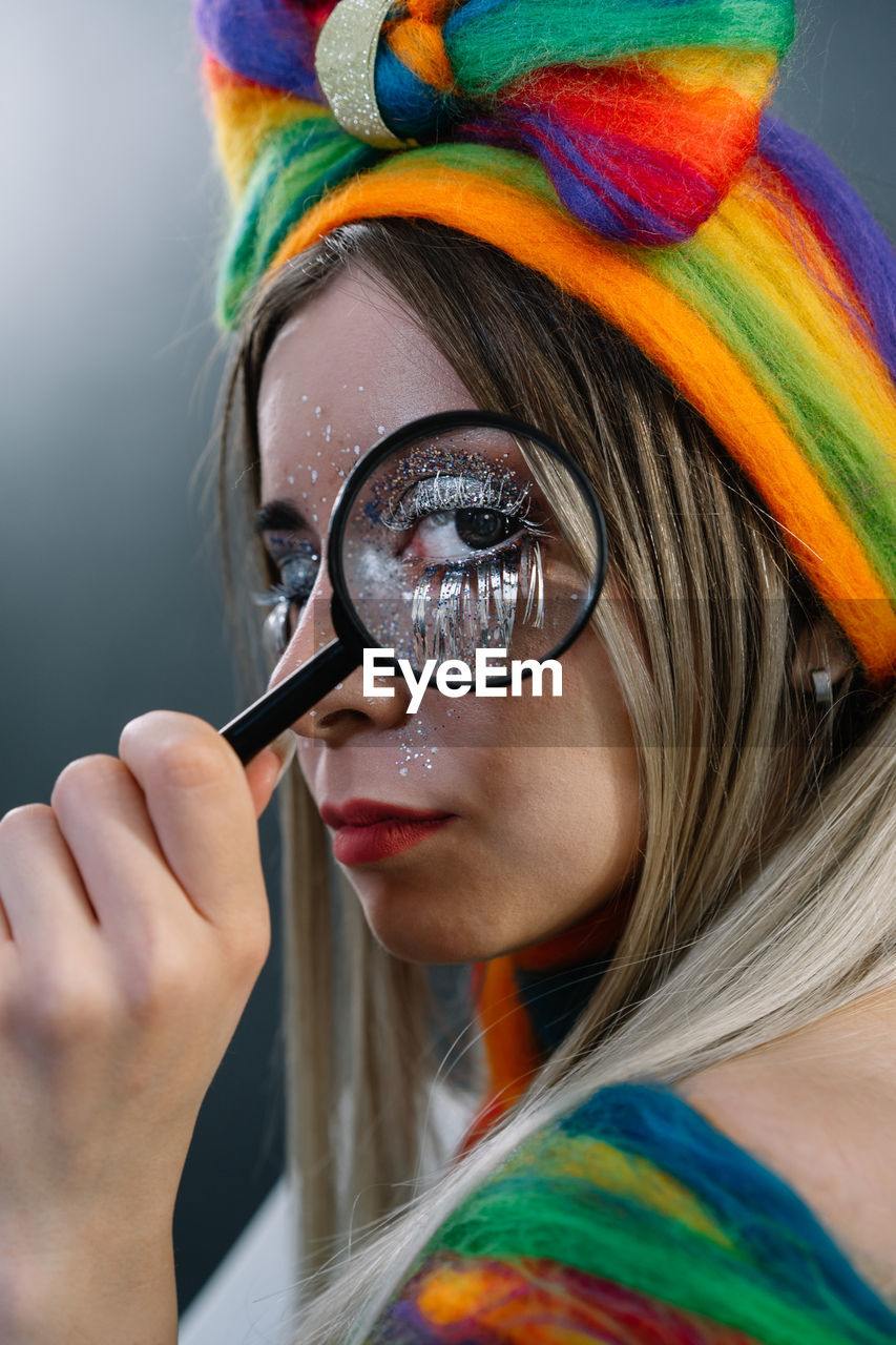 Close-up portrait of young female model holding magnifying glass