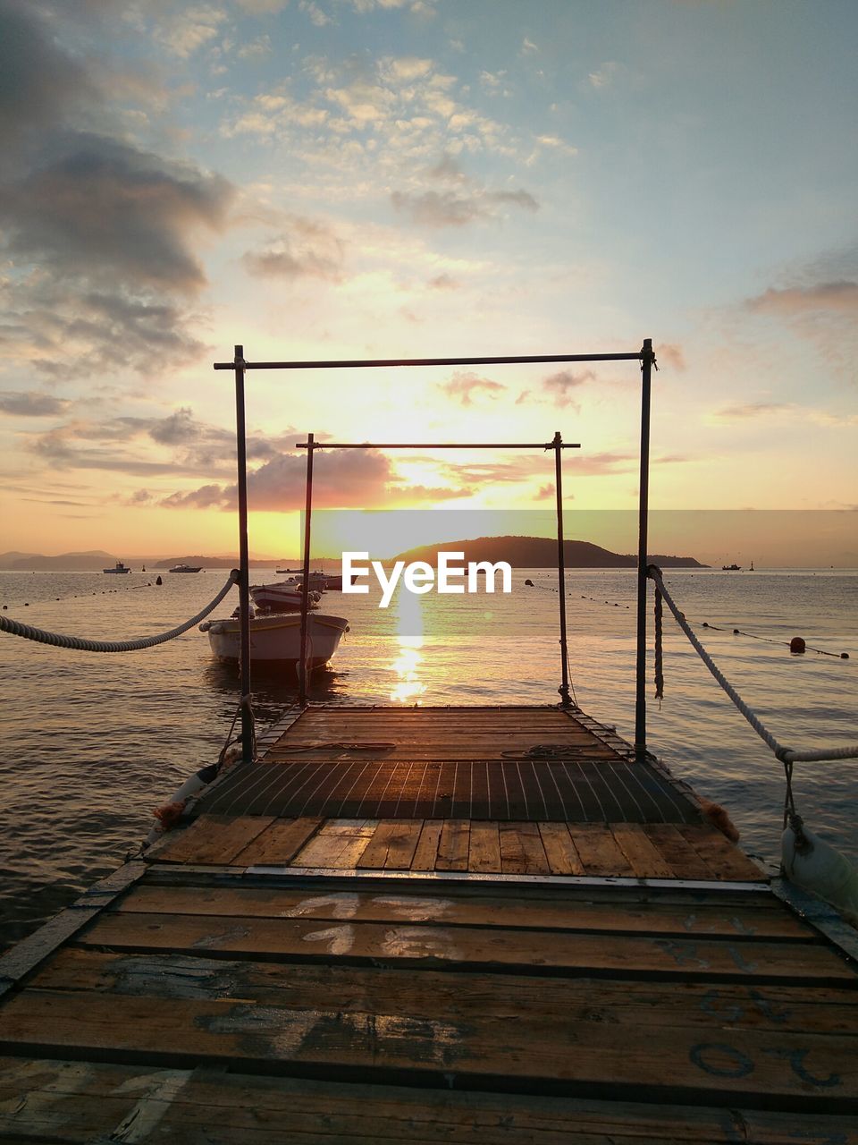 Jetty in sea against sunset sky