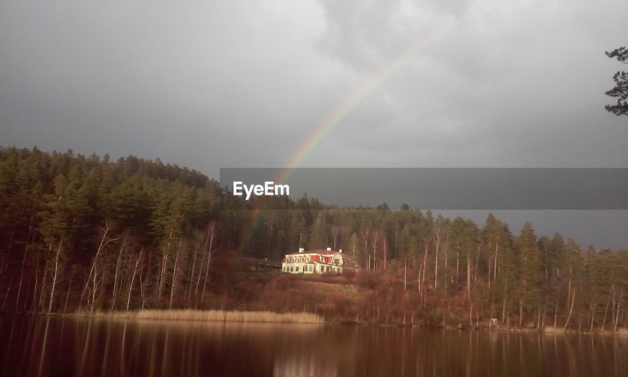 RAINBOW OVER LAKE AND TREES AGAINST SKY