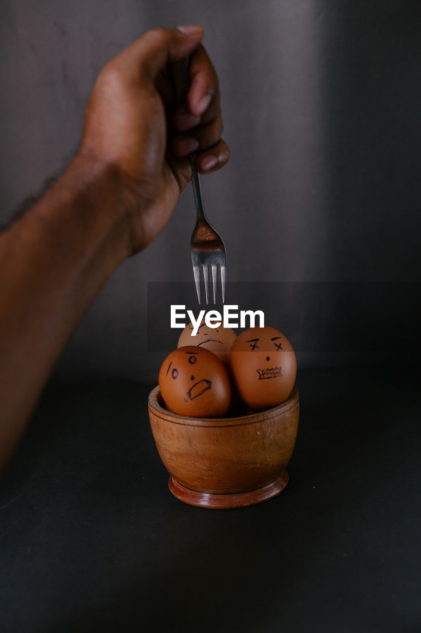 Cropped hand of person braking egg on table