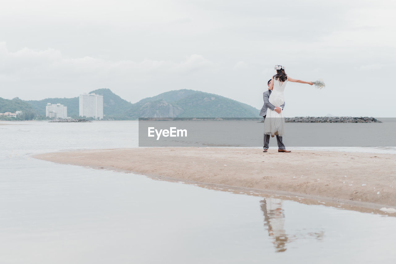 FULL LENGTH OF PERSON STANDING ON BEACH AGAINST SKY
