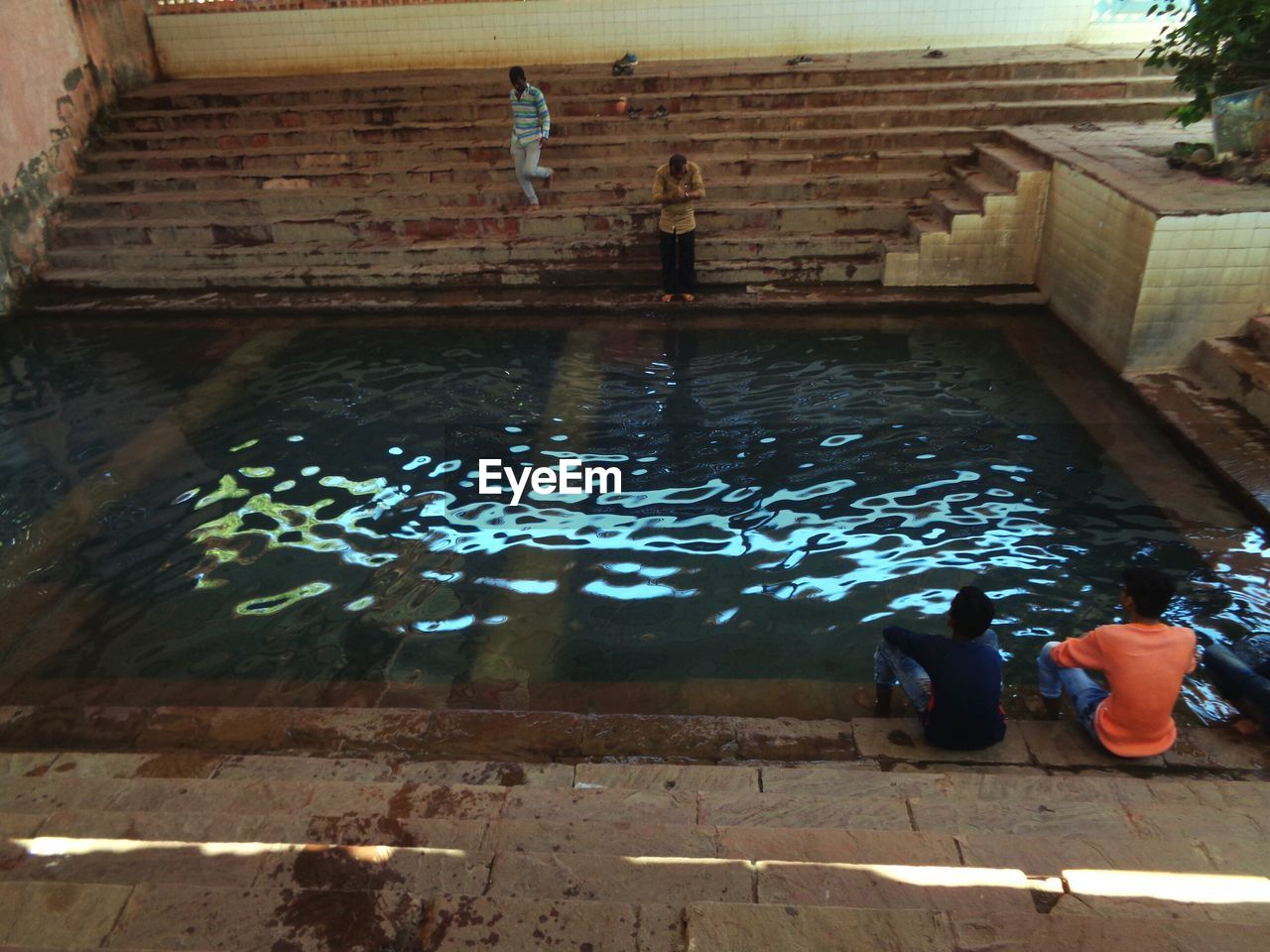 HIGH ANGLE VIEW OF PEOPLE SITTING ON SWIMMING POOL