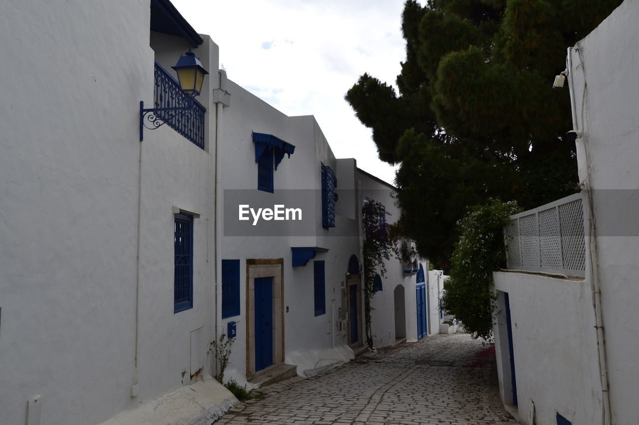 architecture, building exterior, built structure, building, road, street, neighbourhood, town, alley, house, village, residential district, city, sky, nature, no people, facade, cloud, wall, outdoors, plant, urban area, day, tree, residential area, lane, footpath, the way forward