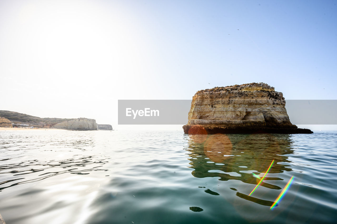 View of rock formation in sea against clear sky