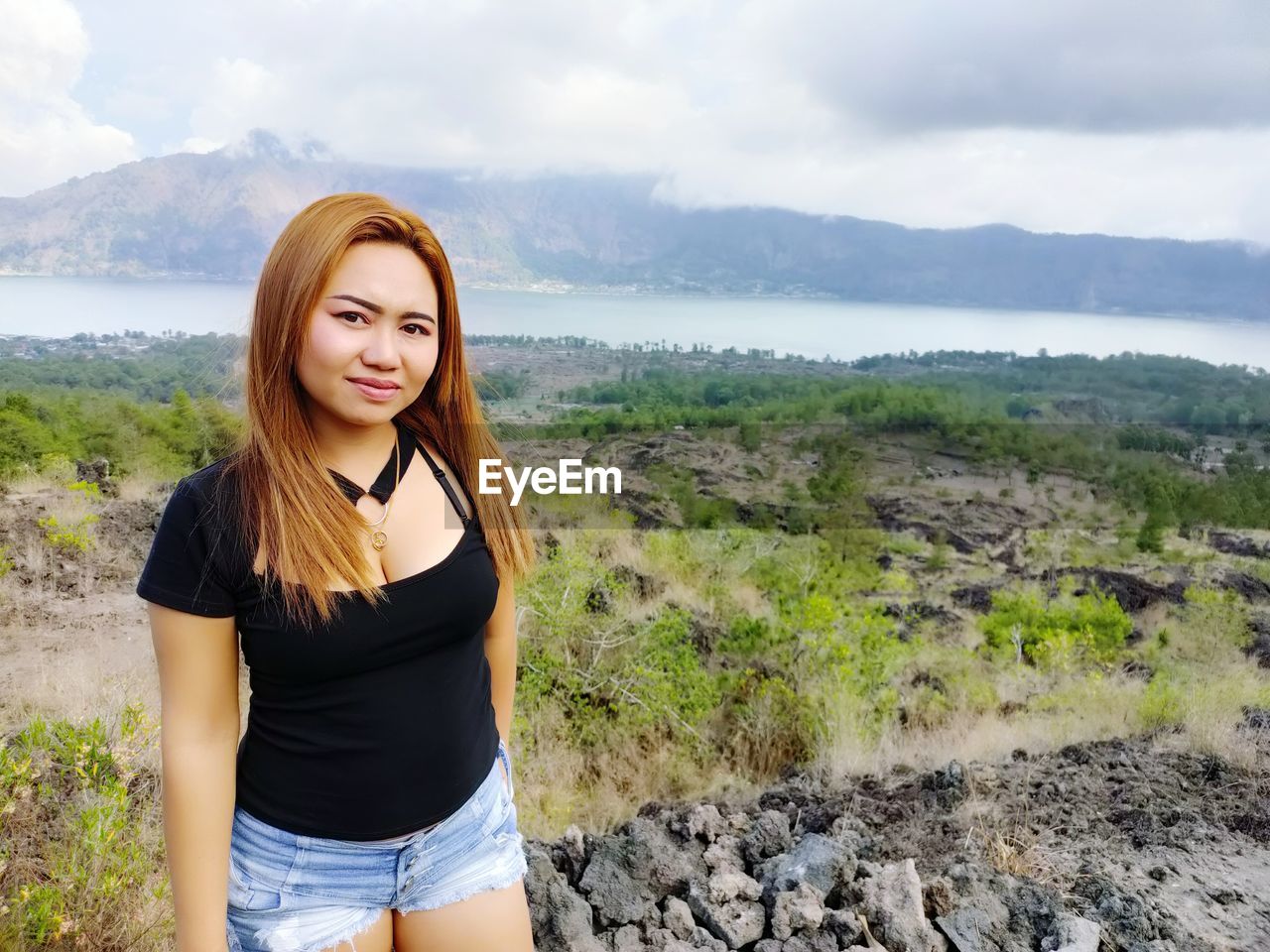 Portrait of beautiful young woman standing on mountain against sky