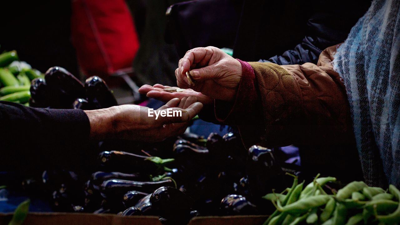 Man giving coin to customer at vegetable stall