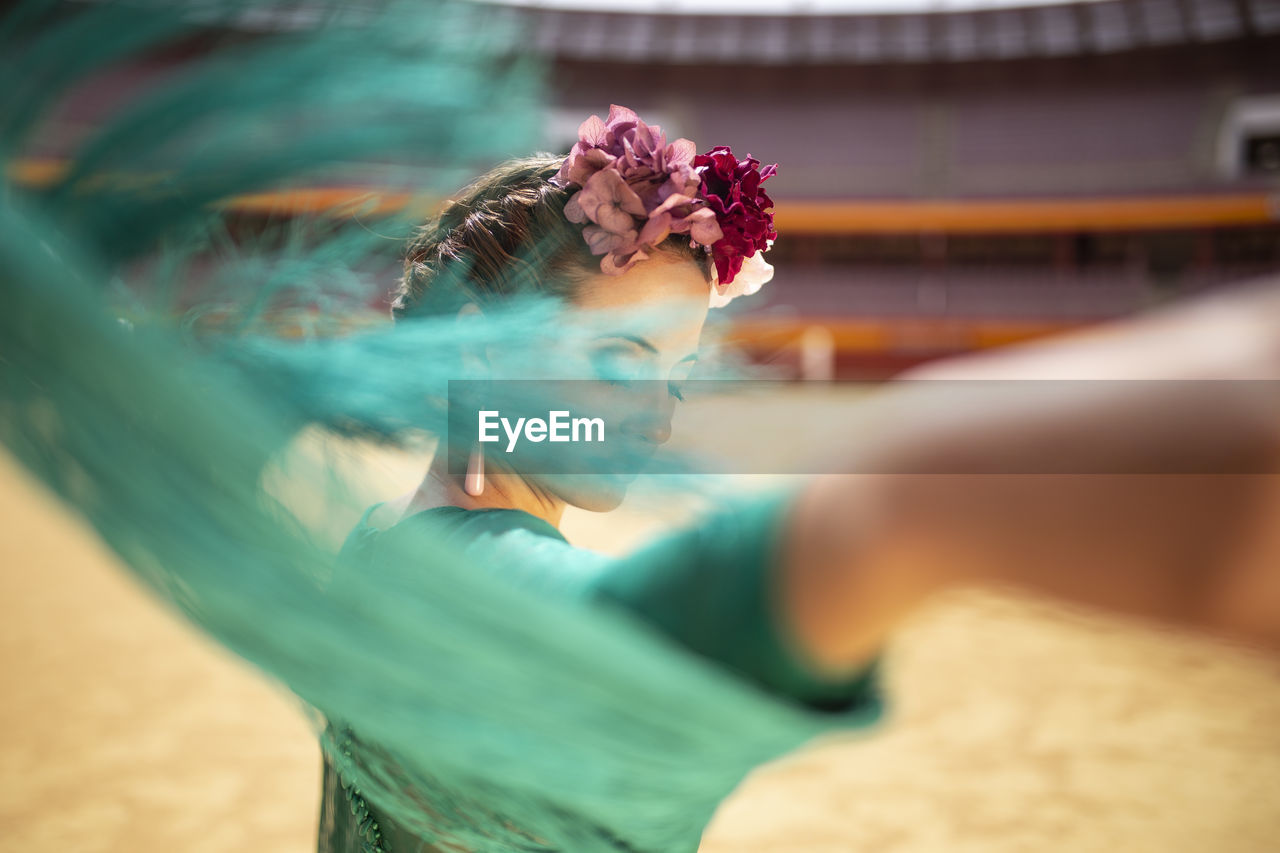 Close-up of flamenco dancer moving her dress's fringes while dancing in bullring