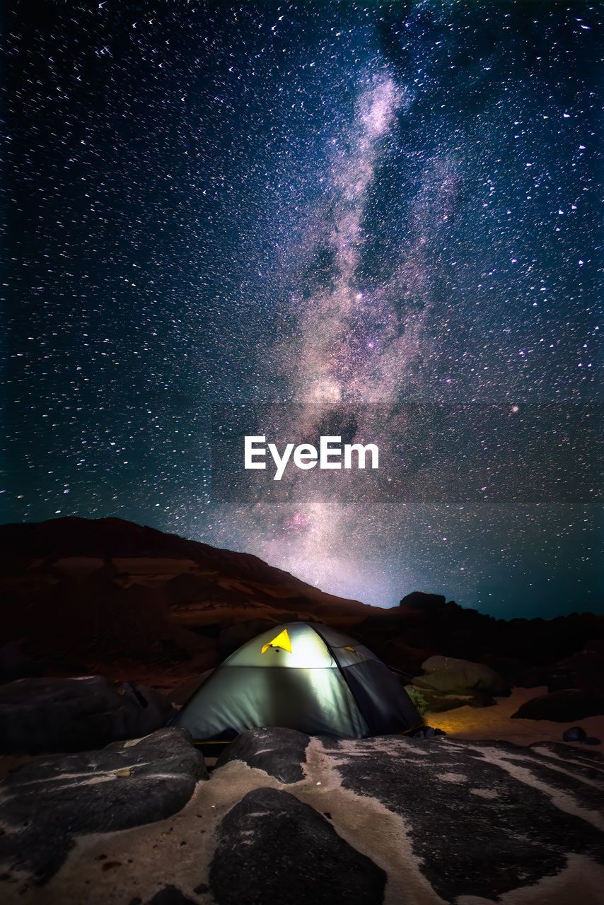 View of the milky way passing over a small tent in the desert