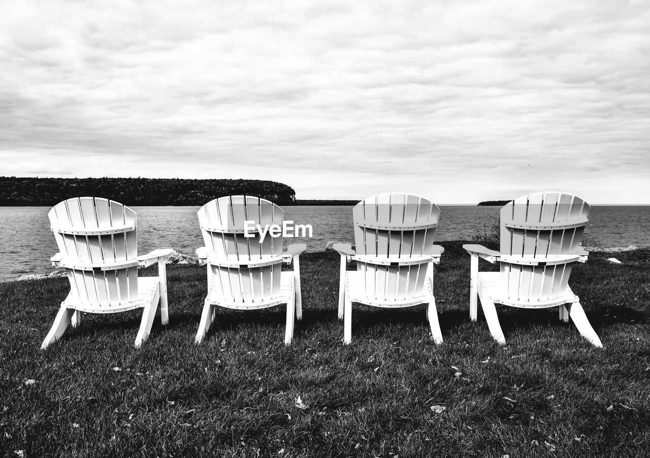 Chairs on grassy field against sky
