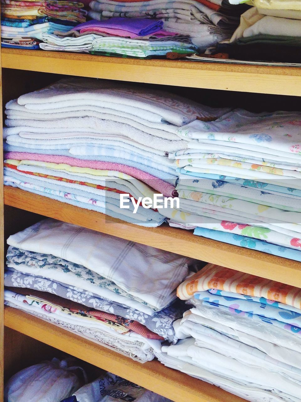 Stack of linens arranged on shelves at store for sale