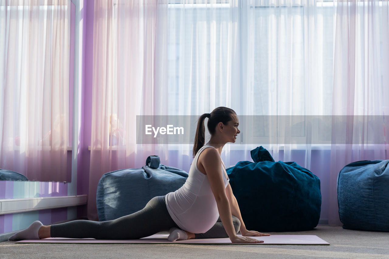Side view of pregnant woman exercising at home
