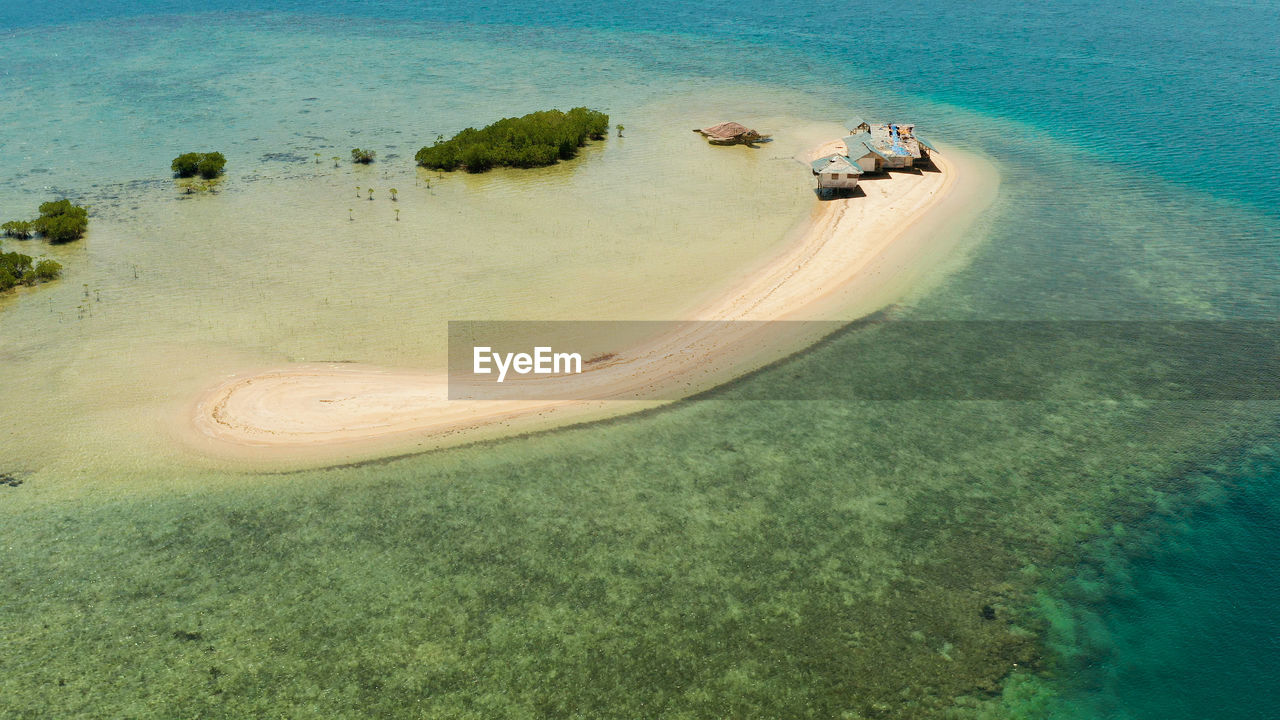 Sandy island with sand bar surrounded by coral reef and blue sea in honda bay, aerial view. 