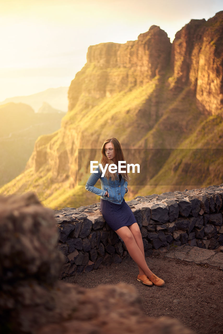 High angle view of woman standing by retaining wall against mountain