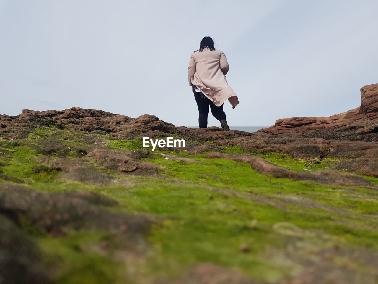 Rear view of woman standing on mountain against sky